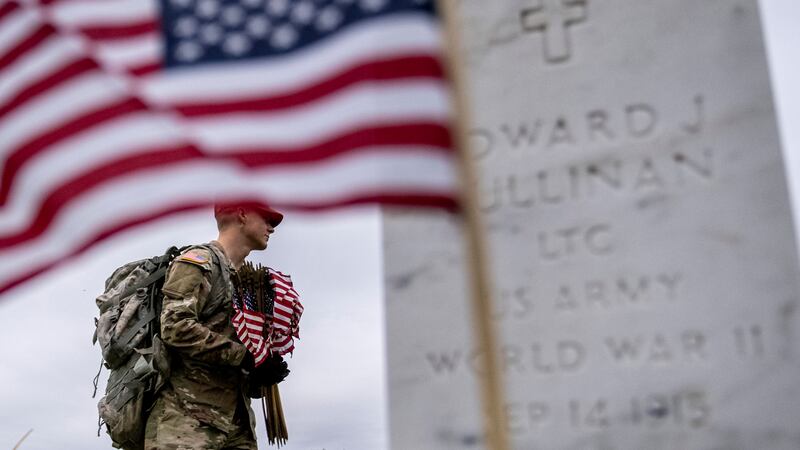 A member of the 3rd U.S. Infantry Regiment, also known as The Old Guard, places flags in front...